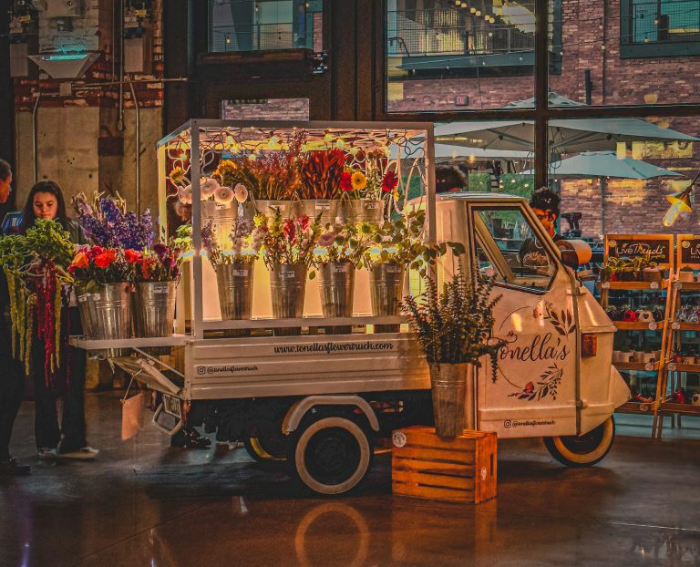 A pickup truck loaded with bundles of fresh cut flowers sits parked, ready for delivery.