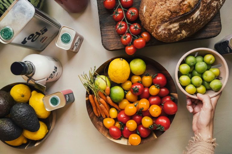 An assortment of fresh seasonal fruits and vegetables is arranged across a table.