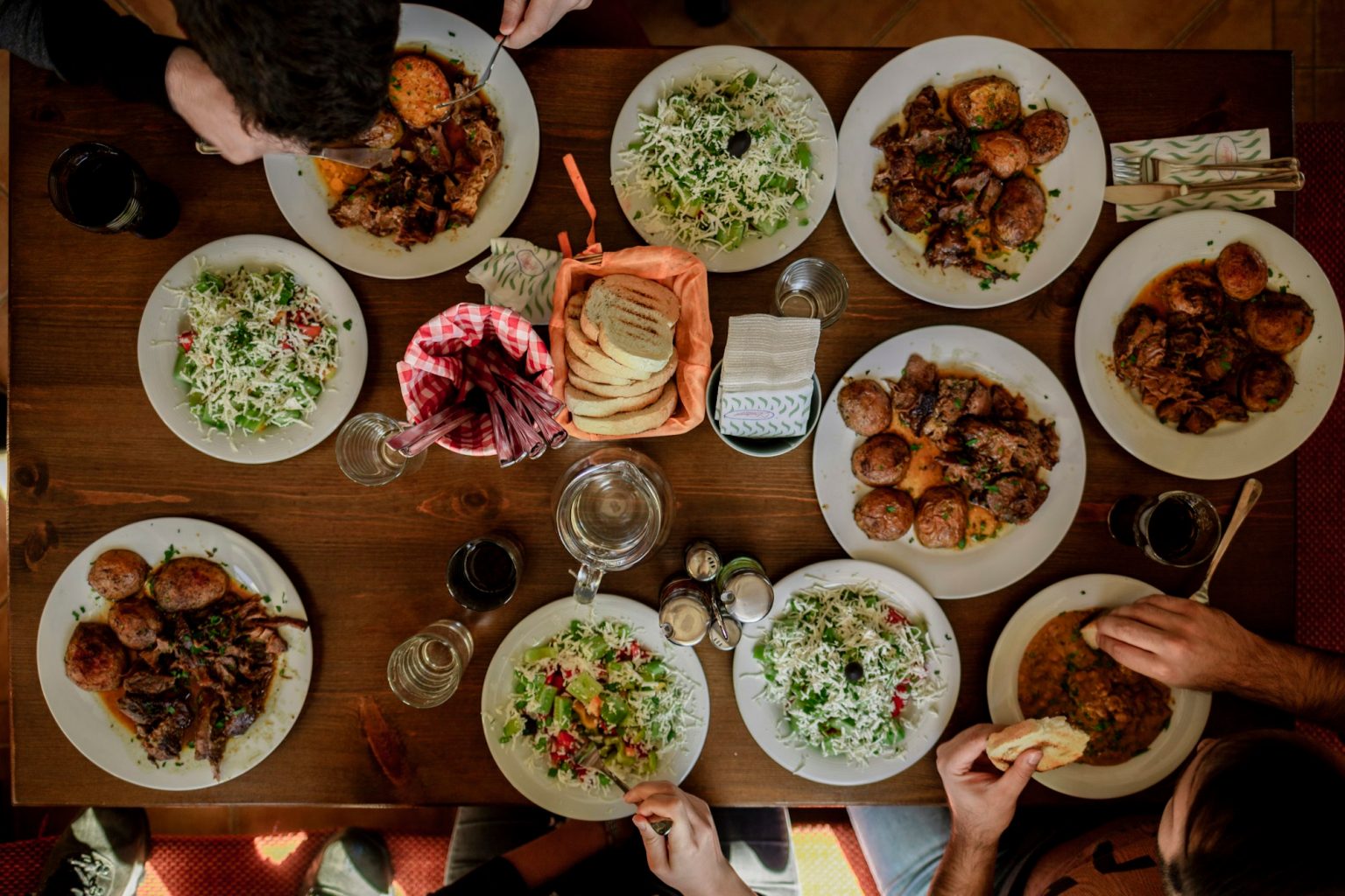 A wooden table is loaded with rustic dishes of food shared family-style, with little else on the surface.