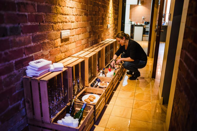 Crates of glassware, napkins and bar stock staged in order along a back hallway before a party.