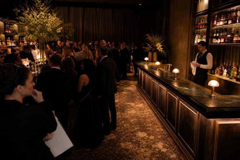 Guests crowd one bar while a second bar across the room stands idle